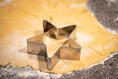 High angle view of the star shaped cookie cutter placed over the rolled dough