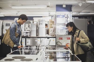 Male and female customer looking at appliances in electronics store