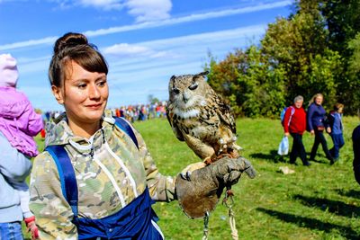 Young woman with eagle owl against sky