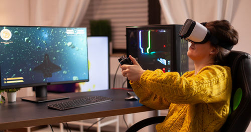 Woman wearing virtual reality simulator while playing video game at home