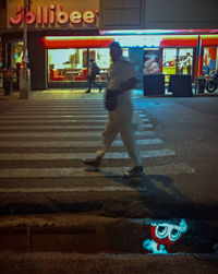 Blurred motion of man walking on illuminated street