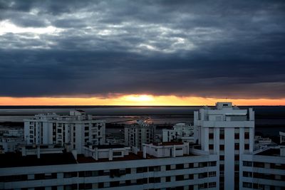 Buildings against dramatic sky during sunset