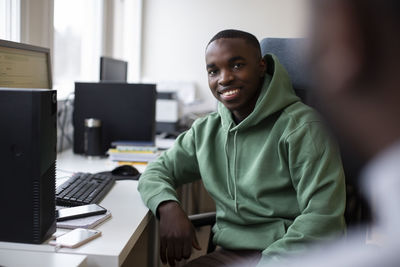 Portrait of smiling male trainee sitting at desk in office