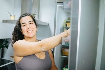 Portrait of smiling woman by refrigerator