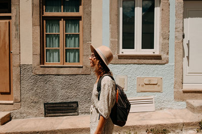 Side view of woman standing against building