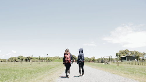 Rear view of women on field against sky