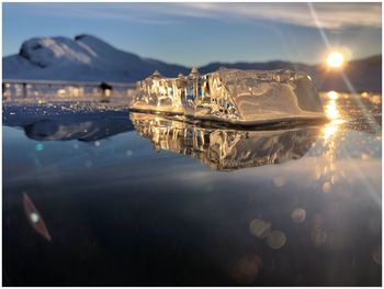 Illuminated city by sea against sky