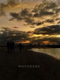 People on beach against sky during sunset