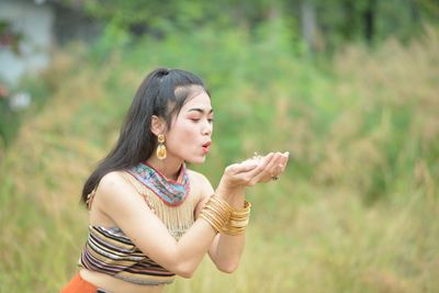 Young woman looking away while standing outdoors
