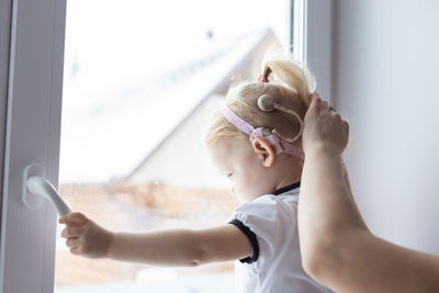 Rear view of deaf girl looking through window