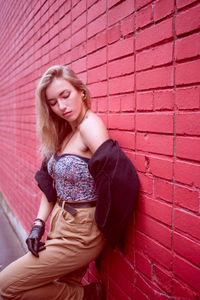 Portrait of young woman standing on wall