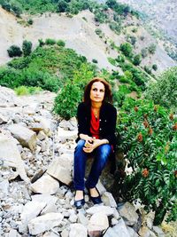 Portrait of young woman sitting on rock