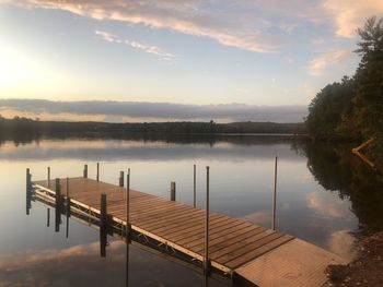 Pier on lake against sky during sunset