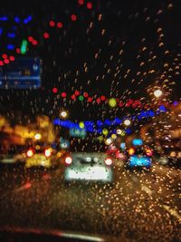 Illuminated city street seen through wet glass window