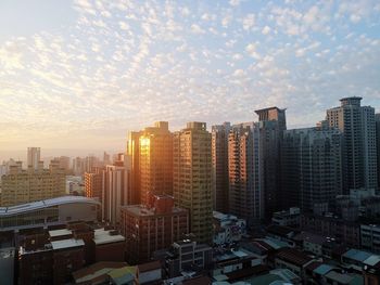 Modern buildings in city against sky during sunset