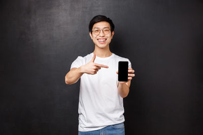 Man pointing at smart phone against black background