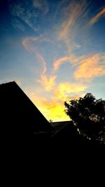 Silhouette houses against sky during sunset