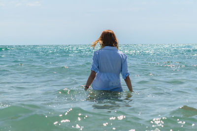 Rear view of woman standing in sea against sky