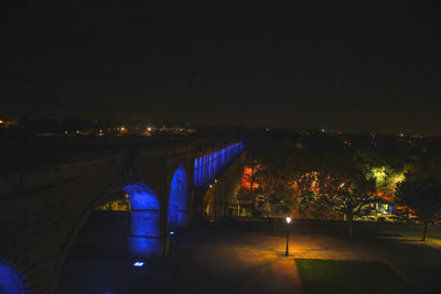 Illuminated bridge over city against sky at night