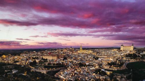 Cityscape against cloudy sky at sunset