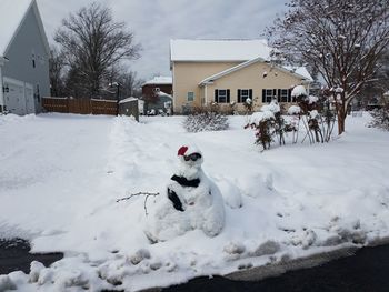 Snow covered houses by building during winter