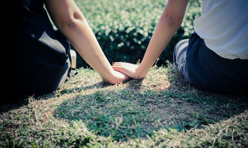 Midsection of couple sitting on field at park