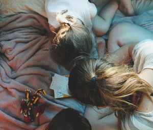 High angle view of siblings sitting on bed at home