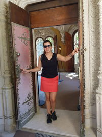 Portrait of smiling young woman standing against wall
