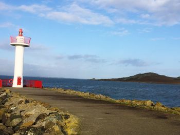 Lighthouse by sea against sky