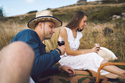 Couple drinking wine while sitting on land