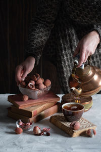 A woman pours tea from a copper teapot into a cup,still life with lychee,cozy