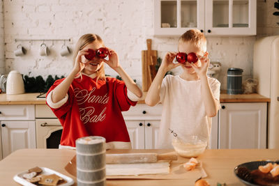 Two teenage children are having fun playing and preparing christmas food for the holiday in kitchen