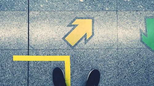 High angle view of shoes on tile floor by arrow sign