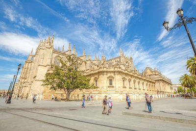 People walking outside historic cathedral against sky