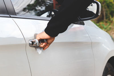 Midsection of man holding camera on car