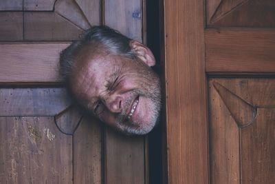 Portrait of senior man peeking through door