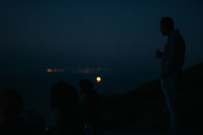 Silhouette people standing against sky at night