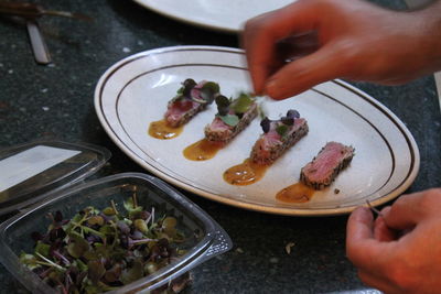 Cropped hand preparing food in plate on table