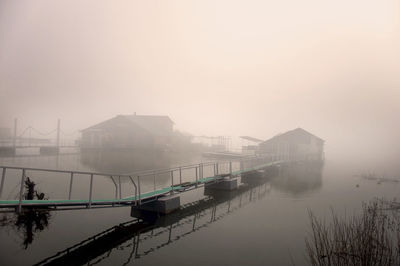 Scenic view of lake by buildings against sky during winter