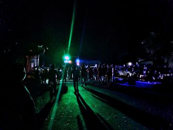 People at illuminated street light in city at night