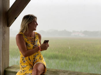 Young woman using mobile phone while sitting on camera