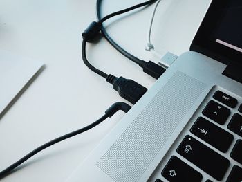 Close-up of usb cables attached to laptop on table