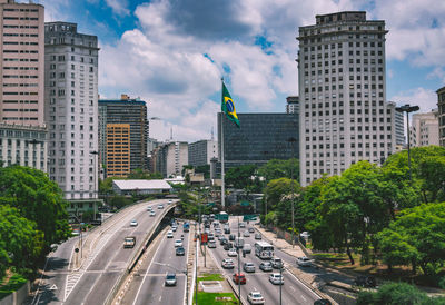 Road amidst buildings against cloudy sky in city