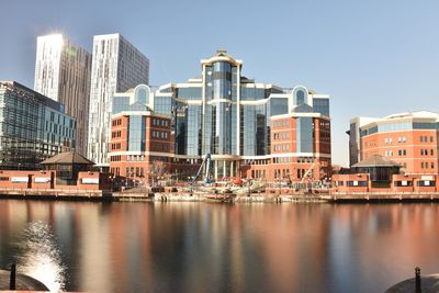 Buildings by river against sky in city