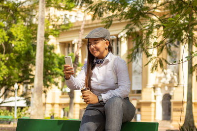 Young man using mobile phone while sitting outdoors