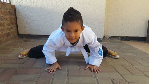 Portrait of cute boy exercising on footpath