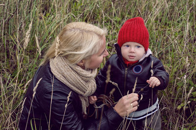 Mom and son in leather jackets walking on the field with dry grass autumn