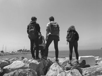 Rear view of people standing on rock against sky