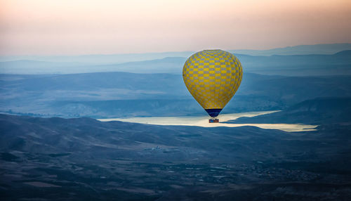 Hot air balloon flying over mountains against sky