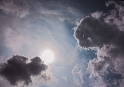 Low angle view of sunlight streaming through clouds